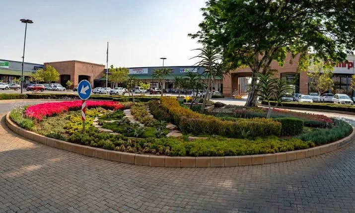 Brick-edged traffic circle planted with massed groundcover, aloes and rockwork at a retail centre entrance