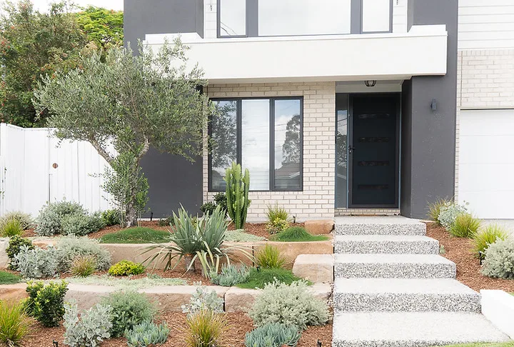 Water-wise front garden with succulents, grasses, stone terracing and exposed aggregate steps
