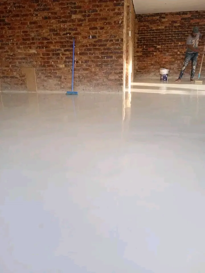 Large seamless light-coloured resin floor being finished in a face-brick commercial interior