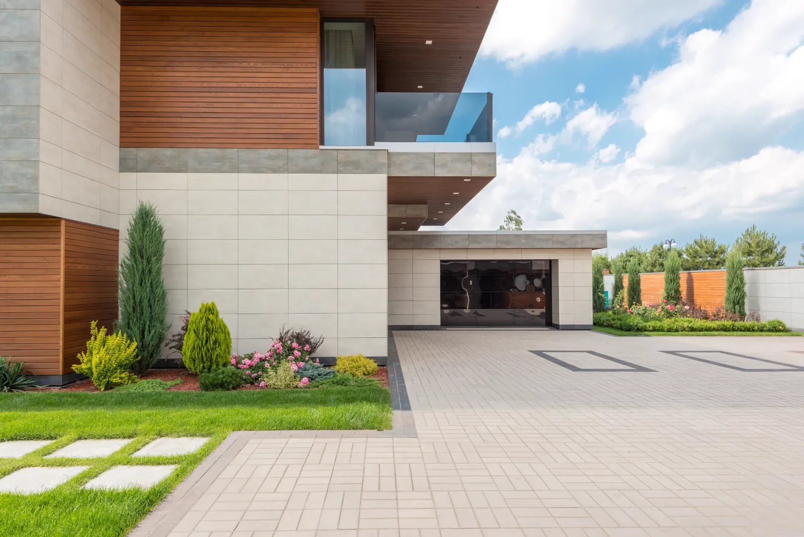 Wide brick-paved driveway in front of a modern home with clipped shrubs and lawn edging