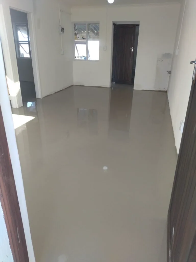 Glossy beige epoxy floor reflecting daylight through a residential living area and passage