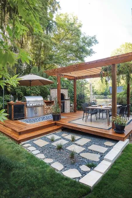 Timber deck with a slatted pergola, built-in braai, outdoor kitchen and dining set beside a stepping-stone path